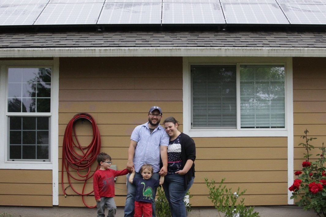 A family of four outside their home with rooftop solar panels, 2018